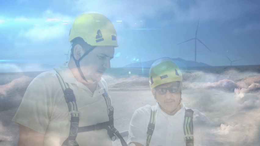 Two male technicians leaning at wind site, holding device and activating HUD overlay over them. Engineers, onsite, outdoor, safety, helmet, harness, network