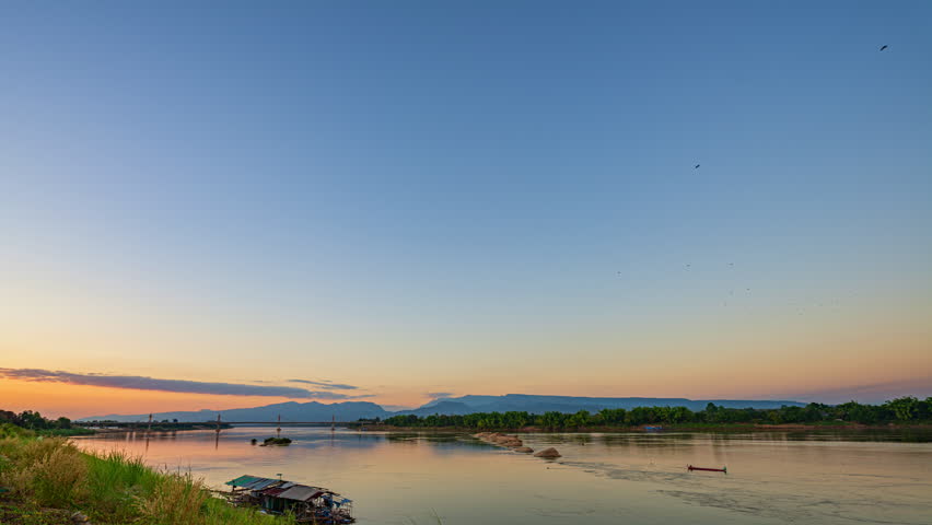 Time lapse A dreamlike sunset casting golden light over the Mekong River and the Fifth Thai–Lao Friendship Bridge in Bueng Kan, creating a surreal and peaceful atmosphere. colorful Reflection