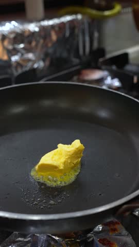Vertical Close Up of Melting Butter Stirred with Wooden Spoon in Frying Pan