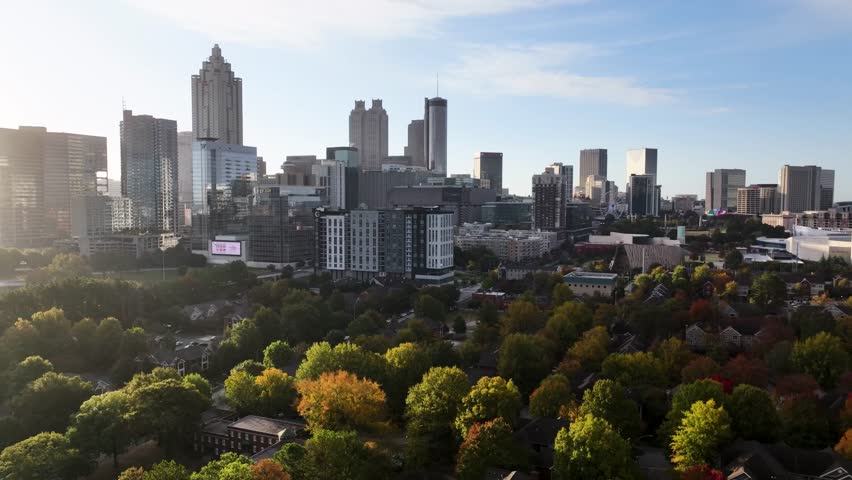 A stunning aerial drone shot capturing the vibrant skyline of Atlanta, Georgia at twilight. The view highlights a busy, glowing highway interchange filled with the dynamic light trails of evening commuters, leading toward the iconic illuminated skyscrapers of the downtown district. This cinematic high-angle perspective perfectly highlights the modern architecture, transportation infrastructure, and electric energy of the metropolis during the beautiful blue hour.