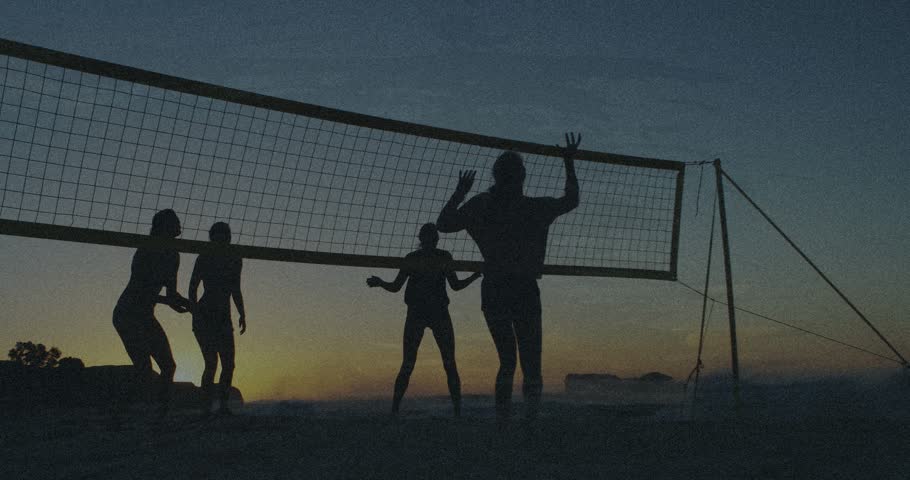 Ball approaching net in beach sports, women jumping, blocking, shifting in sand, trying to score. Volleyball, silhouettes, dusk, outdoor, teamwork, athleticism, spike