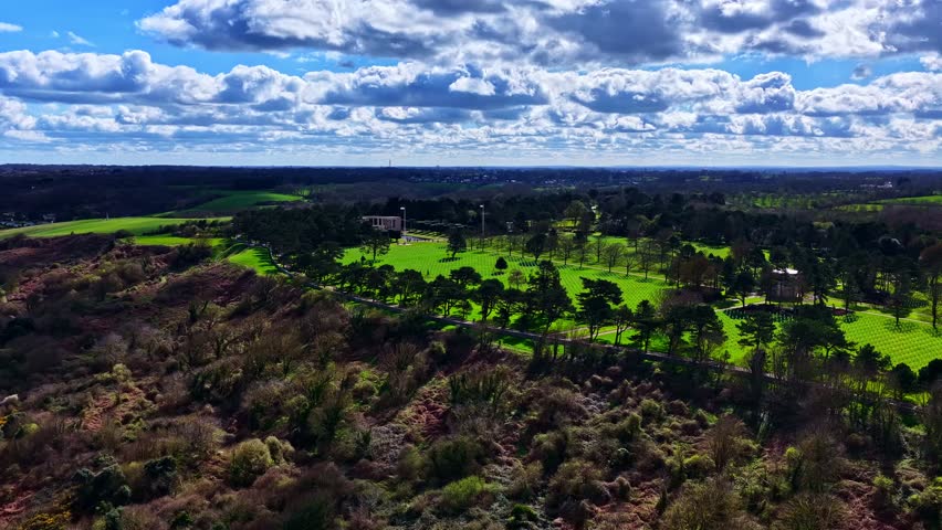 Aerial reveal from manicured parkland to a vast sandy shoreline, capturing dramatic coastal contrast, open natural textures, and sweeping seaside scenery.