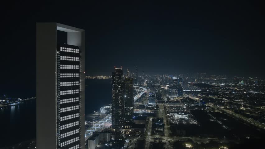 Stunning timelapse of Abu Dhabi skyline at night captured from a high floor vantage point. Illuminated skyscrapers, dynamic city lights, and traffic motion create a vibrant urban atmosphere in the capital of the UAE. Modern architecture, luxury lifestyle, and futuristic cityscape in the Middle East.