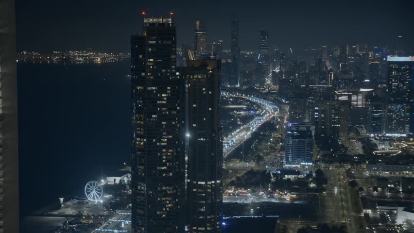 Stunning timelapse of Abu Dhabi skyline at night captured from a high floor vantage point. Illuminated skyscrapers, dynamic city lights, and traffic motion create a vibrant urban atmosphere in the capital of the UAE. Modern architecture, luxury lifestyle, and futuristic cityscape in the Middle East.