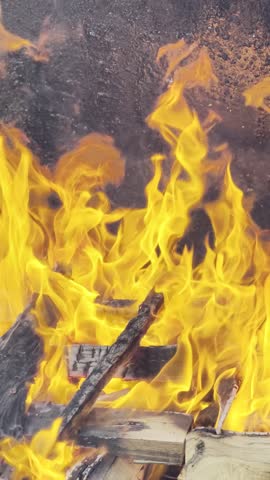Burning firewood with cinematic flames and glowing embers close up, abstract fire texture background, HDR Dolby Vision 4K vertical video high dynamic range footage