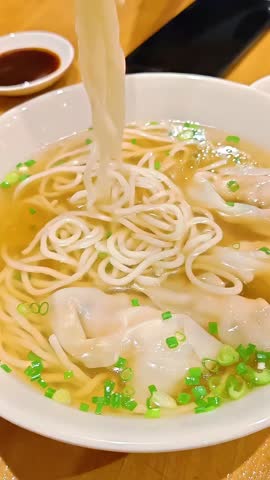 Chopsticks picking up from shrimp steam wonton dumpling bowl, Chinese Food Cuisine, Light Healthy Meal, Scallion Green Onion Garnish