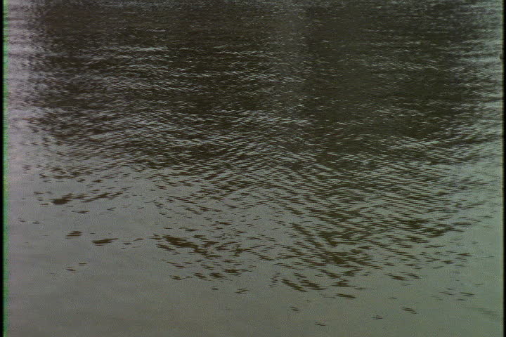 Water fills frame, camera tilts up to the back of Conwy Castle in Conwy, North Wales.