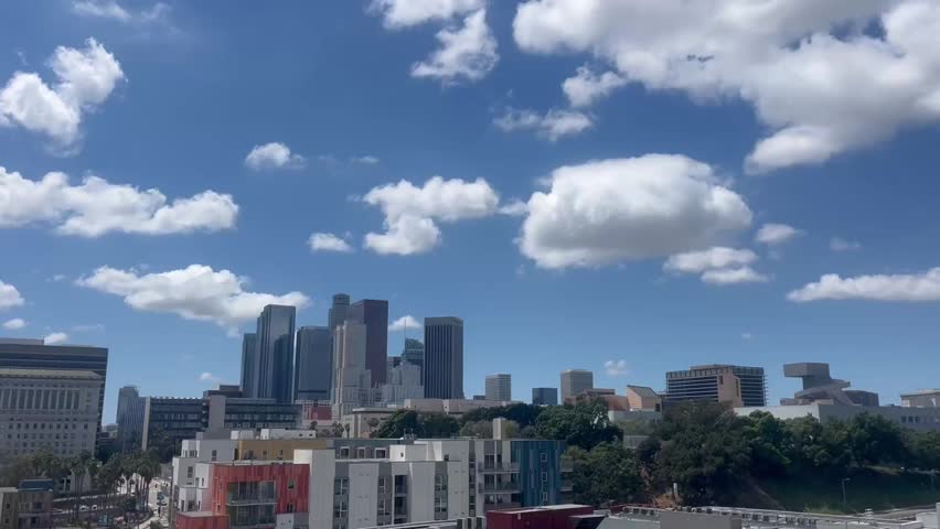 Vibrant cityscape views under a bright blue sky filled with fluffy clouds showcasing urban life and dynamic energy