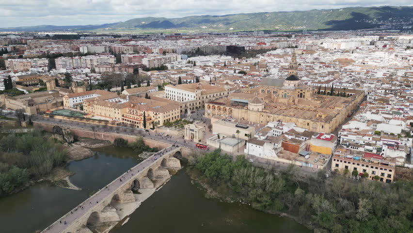 Cinematic aerial panorama of Cordoba featuring Roman Bridge Mezquita and Guadalquivir river, Andalusia province, southern Spain.