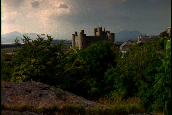 Harlech Castle in background with green bushes in foreground in Gwynedd, North-West Wales.