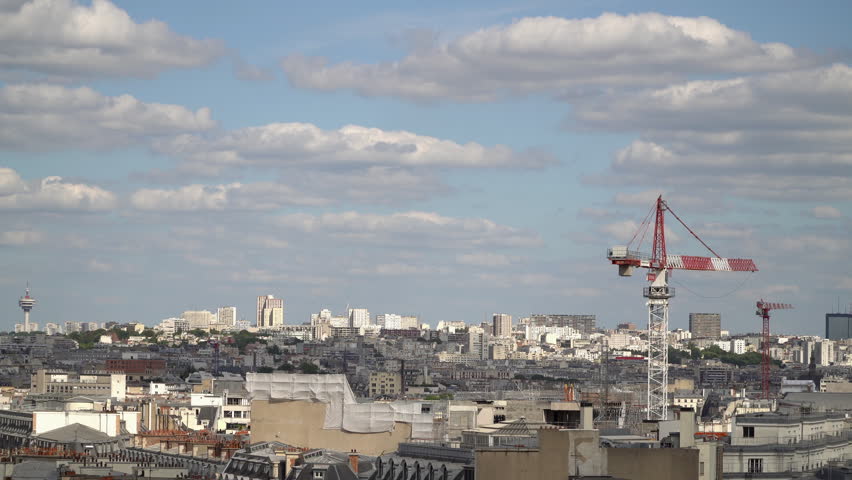 Panoramic view over Paris city roofs under the summer blue sky with scattered clouds.