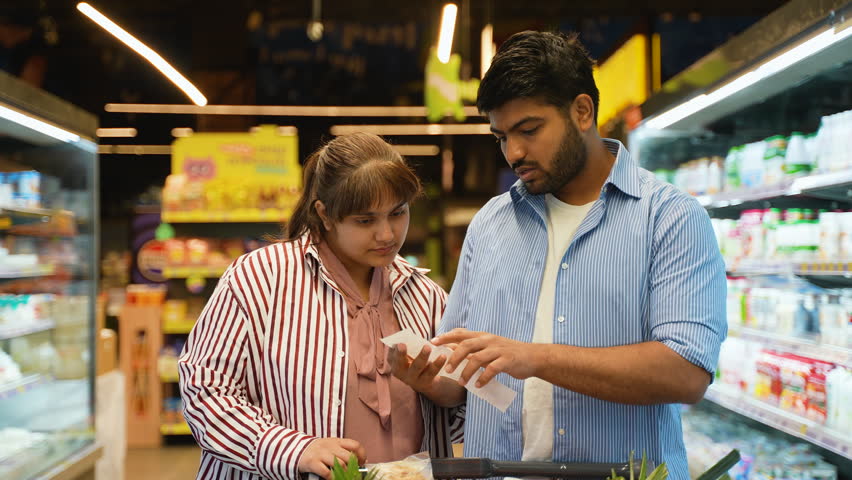 Concerned indian couple checking grocery bill at supermarket
