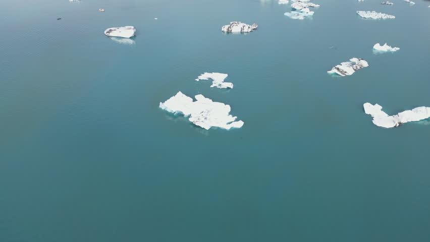 Scattered icebergs floating in deep, dark blue glacial water.