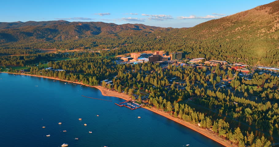 Approaching sunlit waterfront of Lake Tahoe, California, USA. Beautiful nature from drone footage.