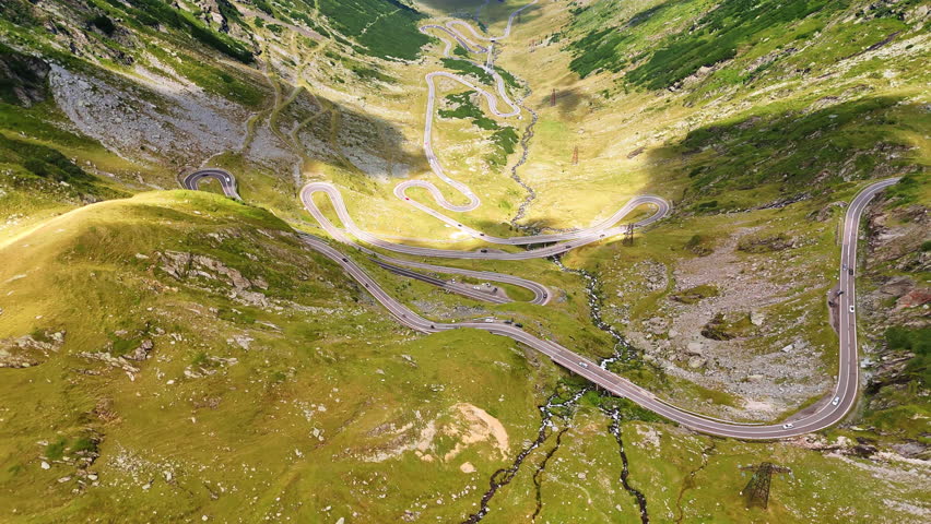 Breath-taking scenery of Transfagarash highway in Romania. Cars go by the road at daytime. Aerial perspective.