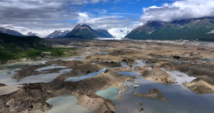 Unreal scenery of wilderness in Alaska, USA. Ice melting in the river surrounded by the stunning mountains coated with clouds.