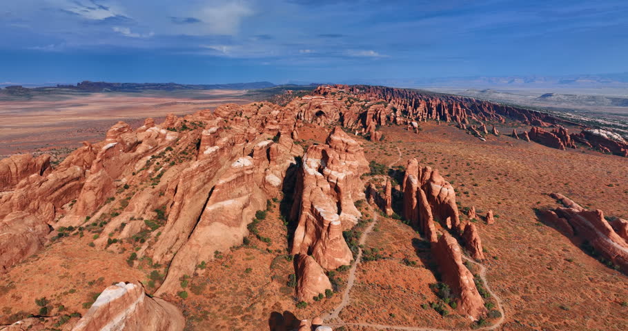 Bright sun lights the rounded canyons in the Arches National Park, Utah, USA. Flight over the red rocks at daytime.