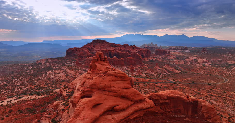 Amazing scenery of the canyons in the rays of setting sun going through the clouds. Aerial perspective on the stunning Arches National Park, Utah, USA.