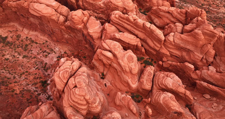 Footage over the rounded tops of the red canyons in the desert. View on the rocks in the Arches National Park, Utah, USA.
