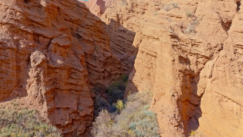 Aerial view between steep slopes of narrow eroded sandstone canyon in Konorchek canyons, Kyrgyzstan.