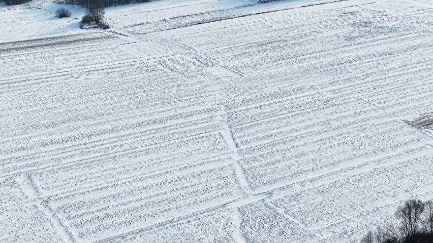 Snow covered agricultural field with tractor track patterns