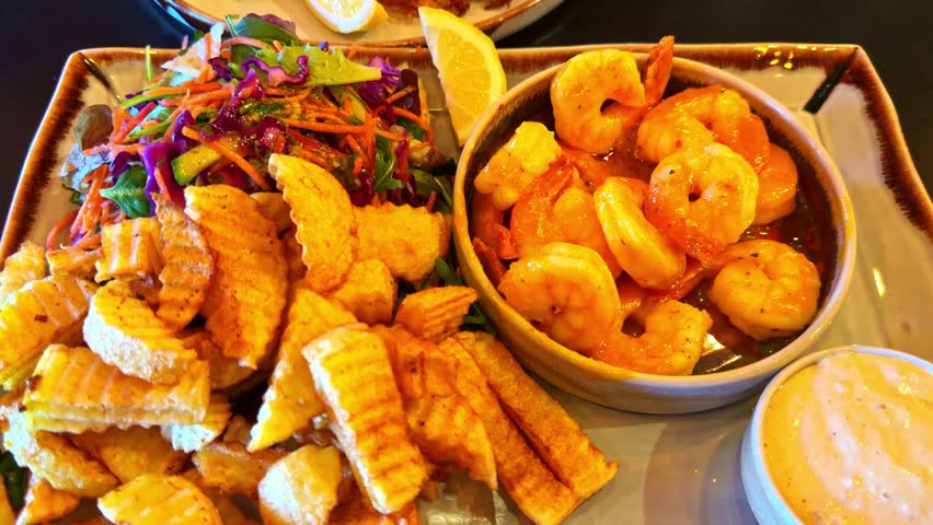 Delicious fried shrimp with waffle fries and salad on a vibrant plate