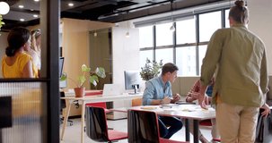 Design team at table placing laptop, checking layouts as light band sliding marking docs for review. Collaboration, office, openplan, brainstorming, professionalism, modern, coworkers - Powered by Shutterstock - Get 15% off with code: PIKWIZARD15