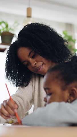 Caring African American mother teaching her little daughter how to draw with colored pencils at home, enjoying a creative family activity. Vertical