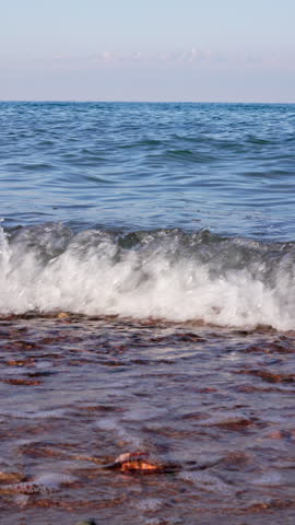 Serene view of calm waves lapping at the shores of Issyk-Kul Lake. The tranquil water reflects the peaceful nature of this off-season setting.