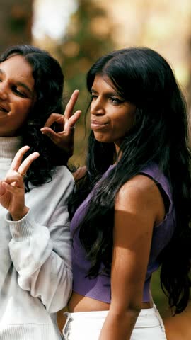 Two beautiful young indian sisters laughing and spending quality time together. Cheerful female friends enjoying their company in a park