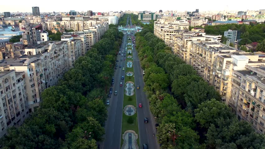 Wide boulevard near palace of the parliament in Bucharest Romania with traffic and socialist era apartment blocks, main road with park and greenery area, urban avenue with trees and cars, city