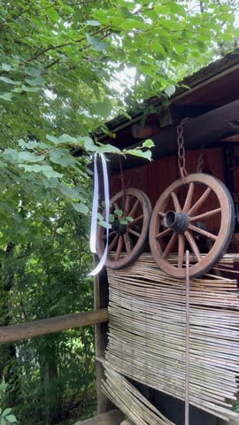 Vlkolínec, Slovakia – August 23, 2025: Traditional wooden wagon wheels hanging on a rustic shed with a white wedding ribbon on a tree branch