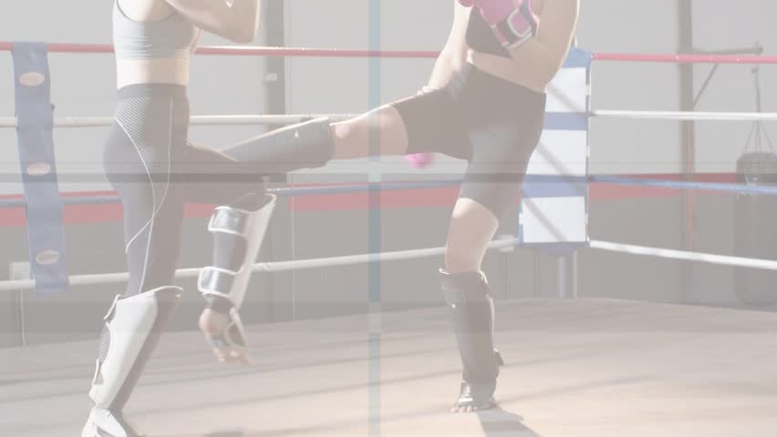 Two female fighters sparring in boxing ring, pink gloves initiating jabs, coach observing training. Gym, kickboxing, combat, shinguards, footwork, focus, discipline