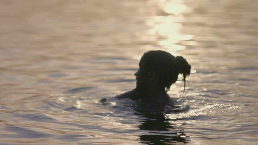 Two sisters splashing water playing in the lake at sunset background