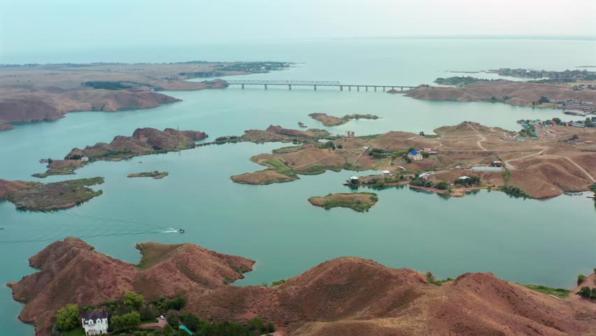 aerial panoramic view of reservoir with small islands and bridge, natural landscape in Kazakhstan, summer scenery, blue water and dry hills, travel destination, environment and nature concept