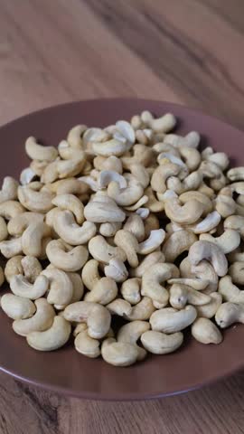 Cashew nuts in a brown bowl, a healthy and delicious snack providing energy and essential protein. selective focus
