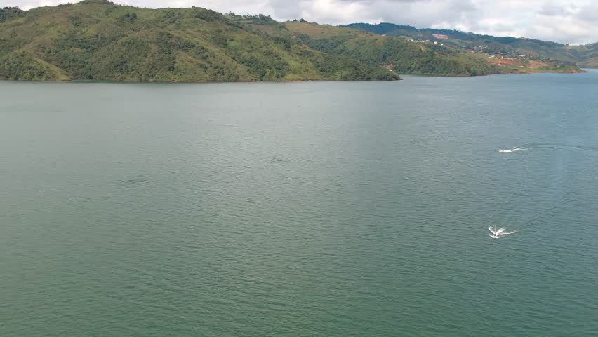 Aerial view of a floatplane taking off from a large lake surrounded by green mountains