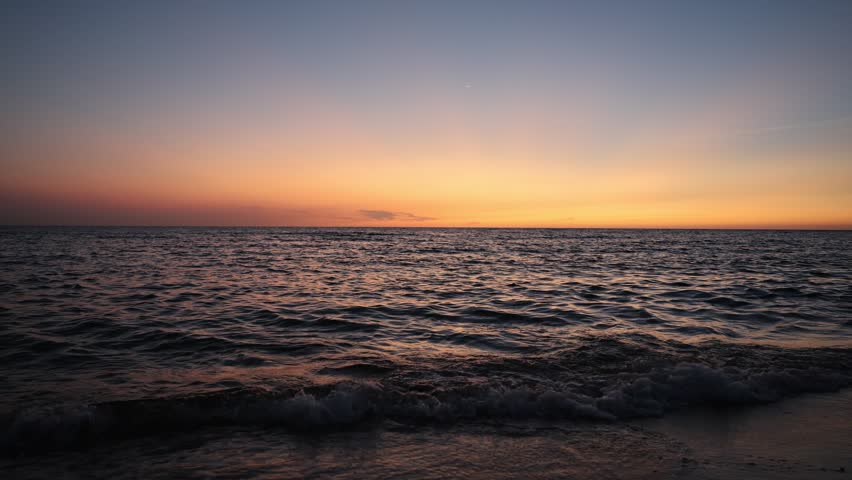 Cinematic sunset over the Red Sea with calm ocean waves and orange - 4K video