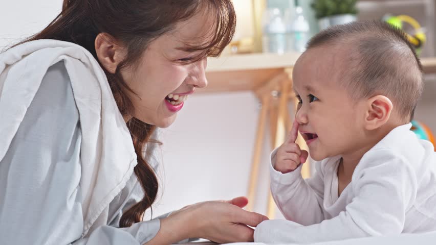 Tender mother baby bonding Asian family motherhood infant care parent child connection at home, joyful parenthood playful interaction on bed, warm natural light cozy lifestyle emotional connection