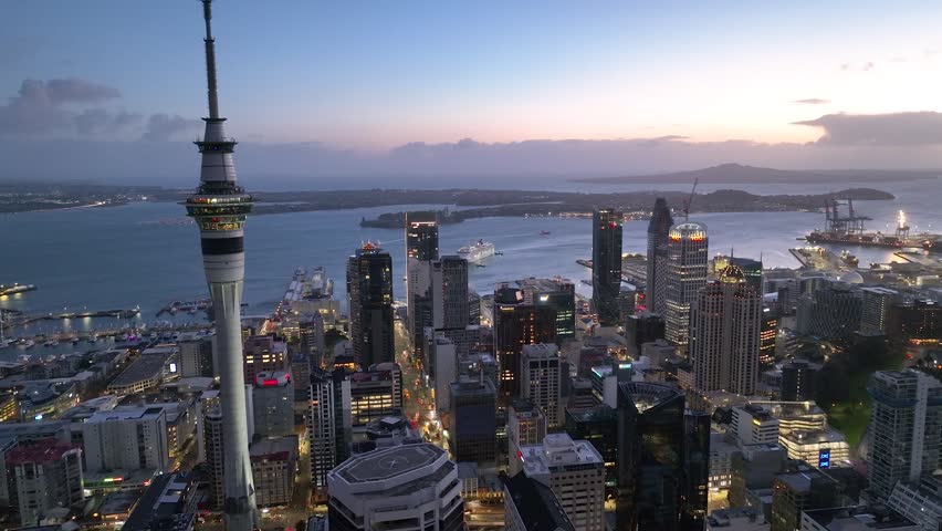 Dolly Flight through Auckland , New Zealand. Skyline. New Skyscrapers. Urban Canyon in Sunset or Sunrise Light. Aerial Pedestal in Establishing Night Drone Shot. Glowing street lights