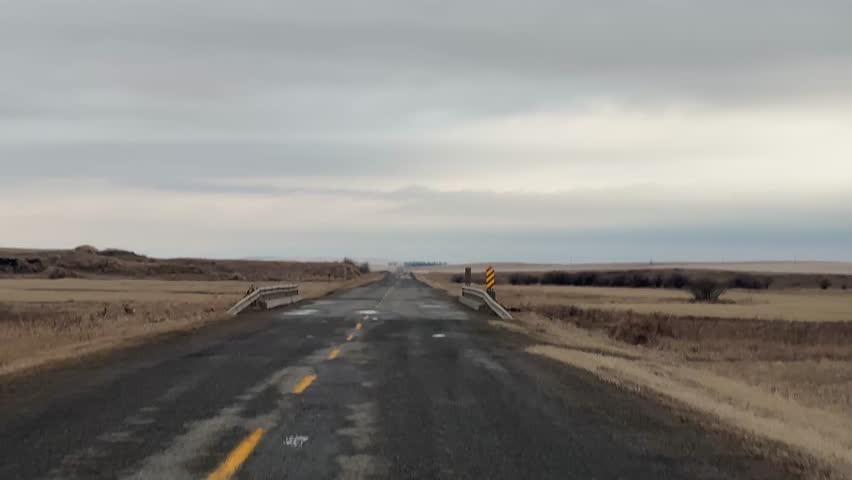 Quiet rural highway stretching through open farmland Alberta
