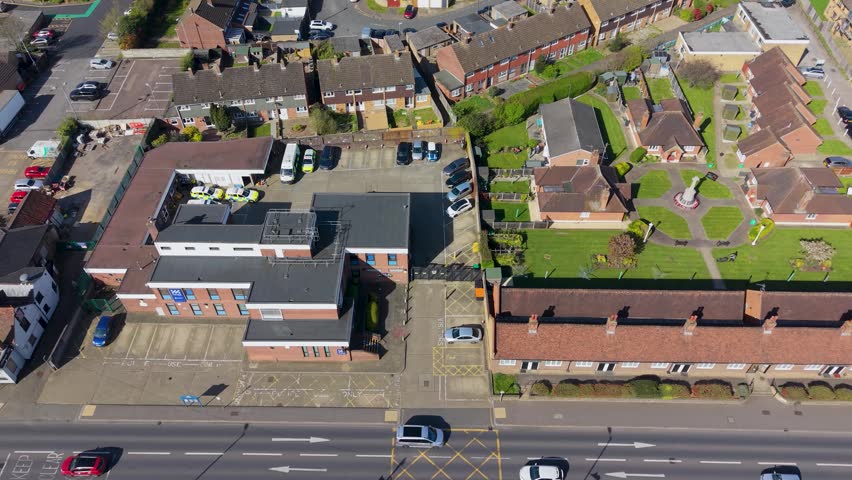 Cheshunt police station aerial orbit showing the station buildings, car park and nearby almshouses along the main road in Hertfordshire, England on a clear day.