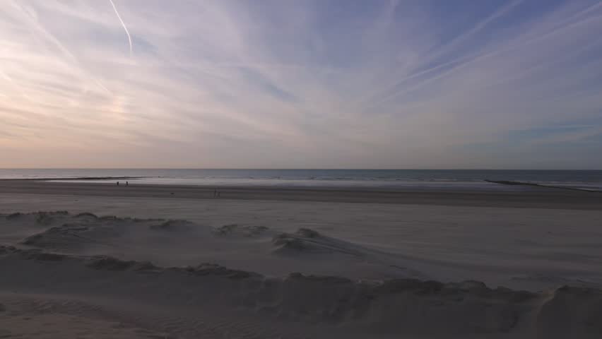 Serene Seascape at Dusk with Dramatic Sky, Sand Dunes, and People on the Beach