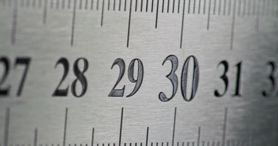 Slow Pan Over Metal Ruler. Smooth slow movement across extreme close-up of brushed metal ruler with black numbers.