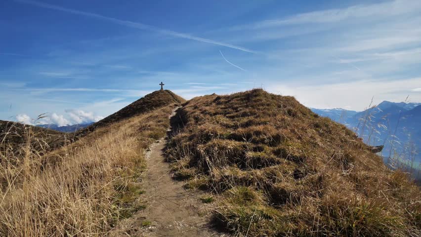 Narrow Mountain Ridge Path Leading to a Summit Cross Under a Clear Blue Sky