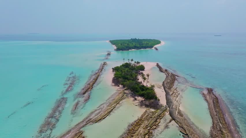 Cinematic aerial drone orbit around a rocky island in the Maldives surrounded by turquoise lagoon and clear ocean with smooth circular motion