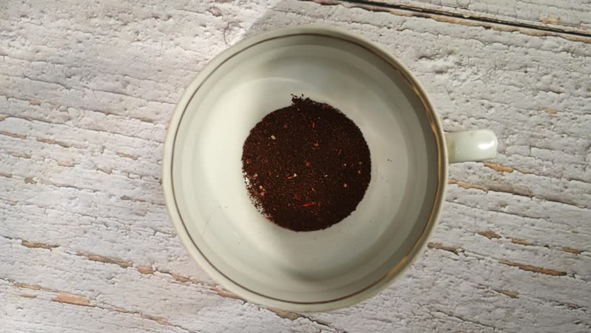 Top view of coffee being poured into a white cup on textured surface. Concept includes ideas of coffee brewing, morning ritual, advertising for coffee shops, cafes, and restaurants.