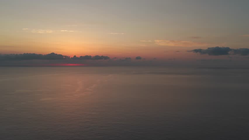 Aerial fly over Mediterranean sea horizon at golden hour in Menorca with calm water and sunset light nature scene