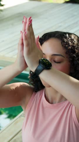 Vertical video: Woman raising palms meditating for health by green pool numbers floating across. Mindfulness, serenity, wellness, female, deck, foliage, vertical video