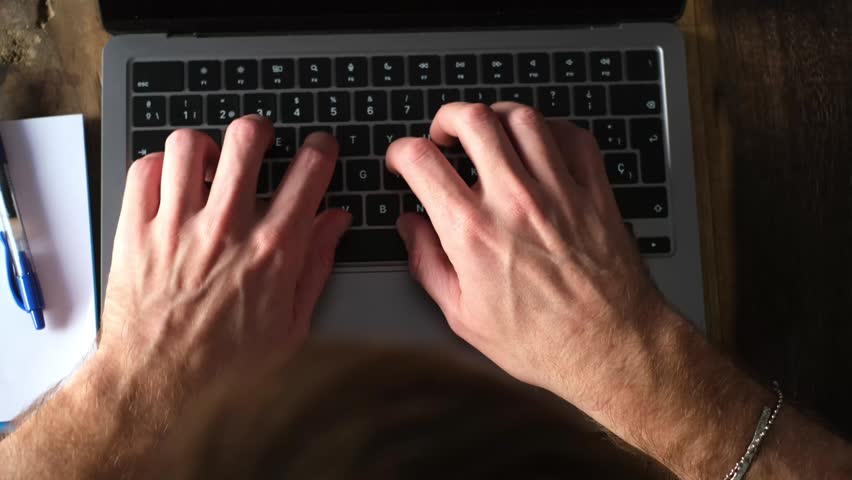Experience the focused precision of professional hands typing on a laptop keyboard. Ideal for concepts of remote work, business productivity, and digital communication in a contemporary office or home environment.